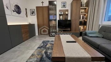 Modernes Wohnzimmer mit stilvollen Möbeln, integriertem TV-Bereich und einem großen Teppich.