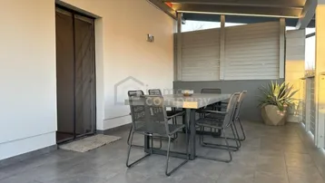 Überdachte Terrasse mit Esstisch und Stühlen, ideal für Mahlzeiten im Freien und Entspannung.