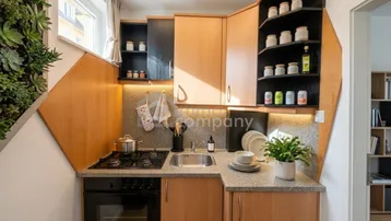 Kleine, funktionale Küche mit Holzschränken, Gasherd und integriertem Backofen, ergänzt durch eine vertikale Pflanzenwand.