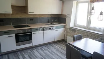 Moderne Küche mit integrierten Geräten, Essbereich und Blick nach draußen durch ein großes Fenster.