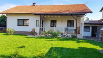 Einfamilienhaus mit großem Garten, Terrasse und Blick ins Grüne unter blauem Himmel.