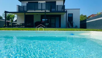 Modernes Haus mit privatem Pool und Terrasse, umgeben von einem gepflegten Gartenbereich.