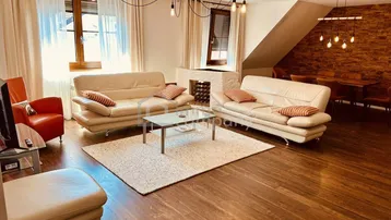 Geräumiger Wohn- und Essbereich mit bequemen Sofas, Holzboden und einem integrierten Weinregal.