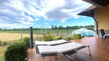 Große Terrasse mit Liegestühlen und Blick auf die umliegenden Felder und einen Pool.