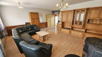 Geräumiges Wohnzimmer mit Laminatboden, Ledersofa und Holzmöbeln.