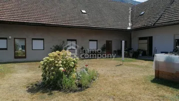Großer Gartenbereich mit Rasenfläche und Blumenbeeten vor der traditionellen Hausfassade.