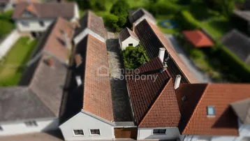 Luftaufnahme mehrerer Gebäude mit roten Ziegeldächern und einem schmalen Innenhof.