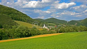 Malerische Landschaft mit grünen Hügeln, einem Dorf und einer Kirche in der Ferne.