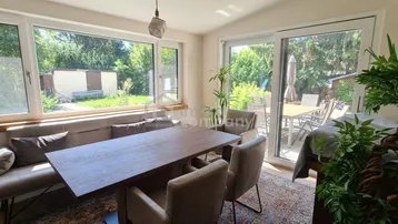 Heller Wohn- und Essbereich mit großem Esstisch, bequemer Sitzbank und Blick in den grünen Garten.