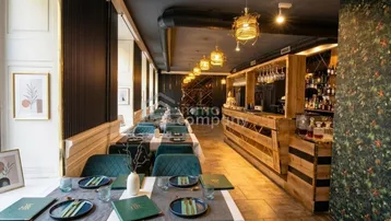 Modernes Restaurant mit elegant gedeckten Tischen, einer stilvollen Bar und großen Fenstern, die viel Tageslicht hereinlassen.