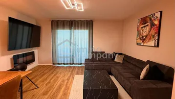 Modernes Wohnzimmer mit großem Ecksofa, stilvollem Holzboden und moderner Beleuchtung.