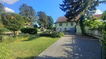 Großzügiger Gartenbereich mit Rasenfläche und Zufahrt zum Haus unter blauem Himmel.