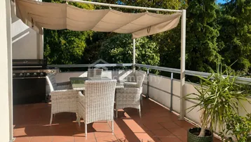 Geräumige Terrasse mit Essbereich, Sonnenschutz und Blick ins Grüne, ideal für Mahlzeiten im Freien.