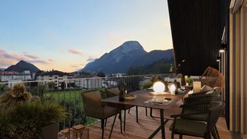 Gemütlicher Balkon mit Esstisch und Stühlen, bietet einen weiten Blick auf die umliegende Berglandschaft.