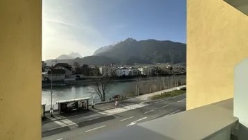 Panoramablick auf den Fluss, die Straße und die majestätischen Berge in der Ferne, eingefasst von der Gebäudestruktur.