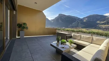 Große Sonnenterrasse mit bequemen Loungemöbeln und atemberaubendem Bergblick.