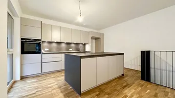 Moderne Einbauküche mit Kücheninsel, integrierten Geräten und hellem Parkettboden.