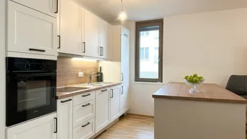 Moderne Einbauküche mit weißen Schränken, Holzarbeitsplatte und integrierten Geräten, ideal für den täglichen Gebrauch.