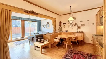 Gemütlicher Wohn- und Essbereich im alpinen Stil mit Holzboden und Zugang zum Balkon.