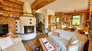 Gemütliches Wohnzimmer im alpinen Stil mit Kamin, Holzbalken und bequemen Sofas.