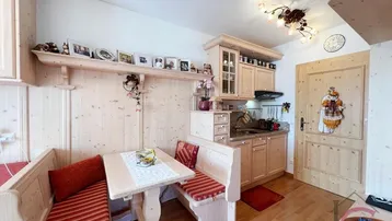 Gemütliche Küchenzeile im Landhausstil mit integrierter Essecke und viel Holzvertäfelung.
