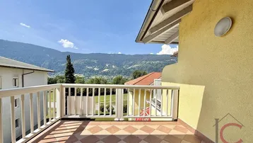 Geräumiger Balkon mit Fliesenboden und malerischem Bergblick unter blauem Himmel.