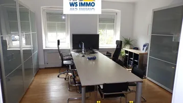 Geräumiges Büro mit Konferenztisch, Stühlen und Schränken, ideal für Besprechungen und Arbeitsbereiche.