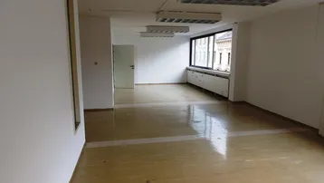 Geräumiger, leerer Büroraum mit großen Fenstern, die viel Tageslicht hereinlassen und einem hellen Boden.