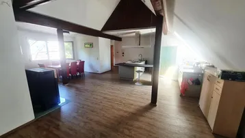 Geräumiger offener Wohn- und Essbereich mit Holzbalken, Küche und viel natürlichem Licht.