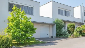 Reihenhäuser mit moderner Architektur, integrierten Garagen und gepflegter Grünanlage.