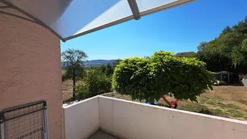 Balkon mit weitem Blick über die Landschaft und grüne Umgebung.