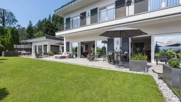 Große Terrasse mit Gartenmöbeln und direktem Zugang zum gepflegten Rasenbereich des Hauses.