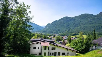 Haus auf einem Hügel mit Blick auf eine malerische Berglandschaft und grüne Umgebung.