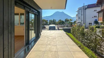 Geräumige Terrasse mit Fliesenboden, Bergblick und Zugang zu einem hellen Innenraum.