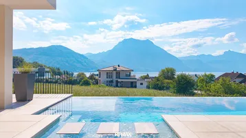 Infinity-Pool mit atemberaubendem Blick auf den See und die umliegende Berglandschaft.