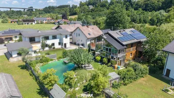Luftaufnahme des Anwesens mit großem Garten, Naturteich und Photovoltaikanlage auf dem Dach.