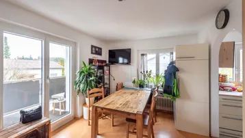 Heller Essbereich mit Holztisch, Balkonzugang und Blick ins Grüne.