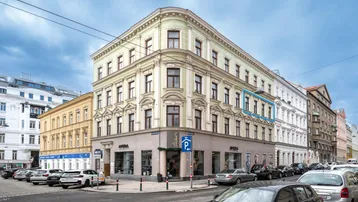 Historisches Eckgebäude mit klassischer Fassade und Geschäften im Erdgeschoss in urbaner Umgebung.