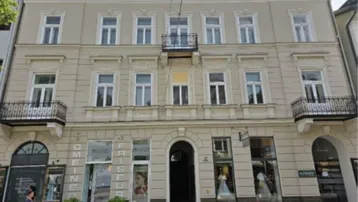 Historisches Mehrfamilienhaus mit klassischer Fassade, dekorativen Elementen und Balkonen in städtischer Umgebung.