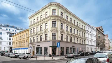 Historisches Eckgebäude mit klassischer Fassade und Geschäften im Erdgeschoss an einer belebten Straße.