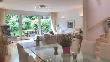 Heller Wohn- und Essbereich mit großen Fenstern, Blick in den Garten und Zugang zur Terrasse.