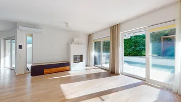 Helles Wohnzimmer mit Holzboden, modernem Kamin und großen Schiebetüren zur Außenterrasse.