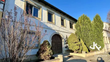Vorderansicht des Gebäudes mit traditioneller Architektur und Holztüren unter blauem Himmel.