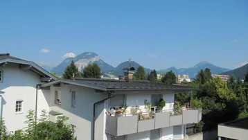 Gebäude mit Balkonen und Bergblick unter klarem blauem Himmel.