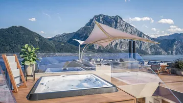 Große Dachterrasse mit Whirlpool, Lounge-Bereich und atemberaubendem Blick auf den See und die Berge.