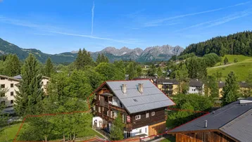 Luftaufnahme eines Neubauprojekts in einer grünen Berglandschaft mit umliegenden Gebäuden.