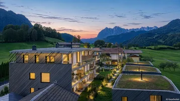 Moderne Wohnanlage mit begrünten Dächern und Bergblick bei Sonnenuntergang.