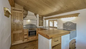 Alpine Küche mit Holzeinbauten, Granitarbeitsplatten und Dachschrägen, ausgestattet mit modernen Geräten.
