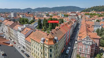 Luftaufnahme der Liegenschaft in städtischer Umgebung mit umliegenden Gebäuden und Bergen im Hintergrund.
