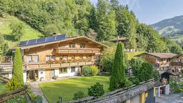 Traditionelles Holzhaus im alpinen Stil mit gepflegtem Garten und Solaranlage auf dem Dach.